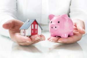 woman holds a piggy bank and a house model