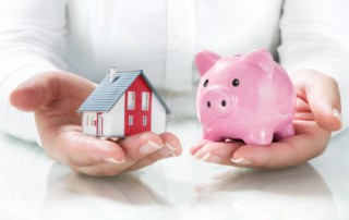 woman holds a piggy bank and a house model